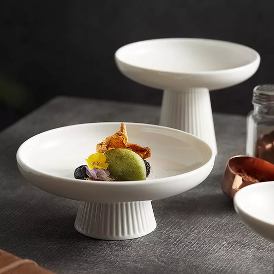 A tall, round ceramic fruit bowl in white